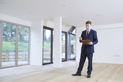 A man dressed in a suit stands alone in an empty room, embodying the essence of professionalism in real estate.